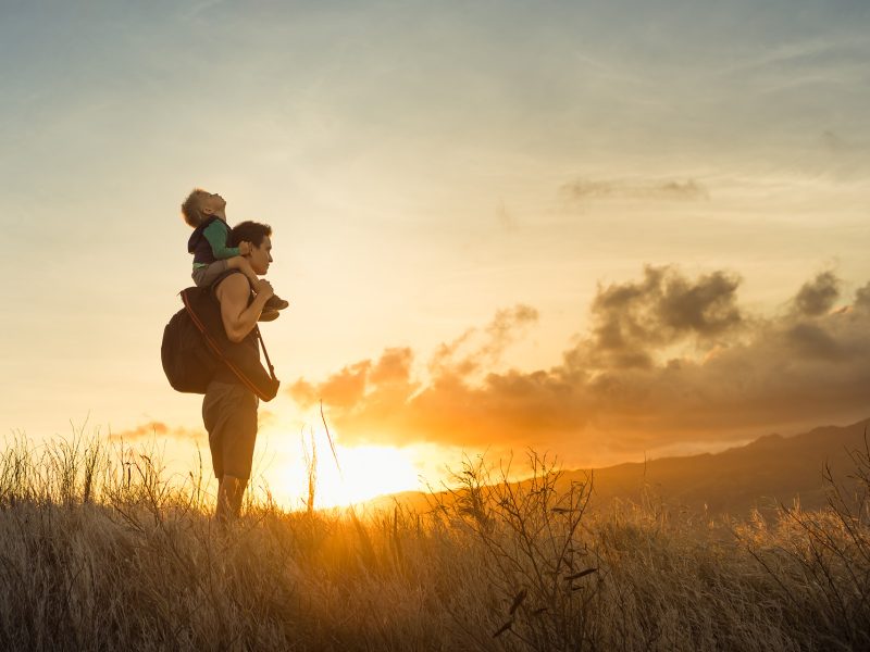 Adventurous father and son standing on a mountain to looking at the beautiful view.